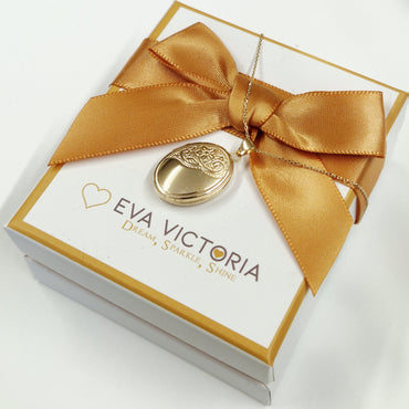 Jewelry box with gold bow and pendant, branded 'Eva Victoria', on a white background