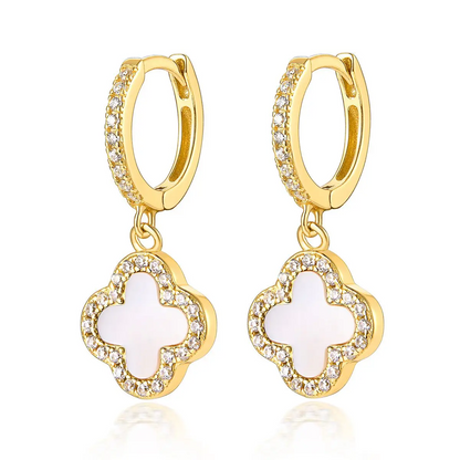 Gold hoop earrings with white clover-shaped charms on a white background