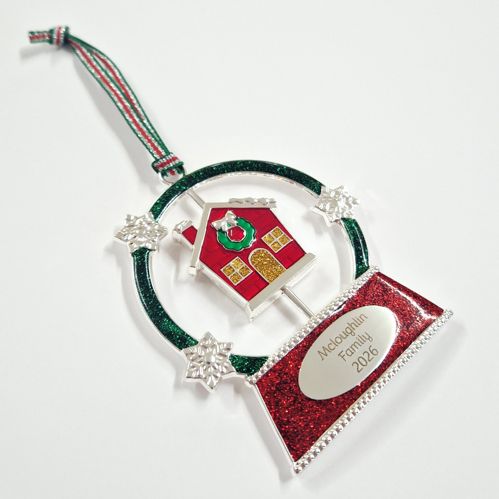 Decorative Christmas ornament with a red house and green ribbon on a white background