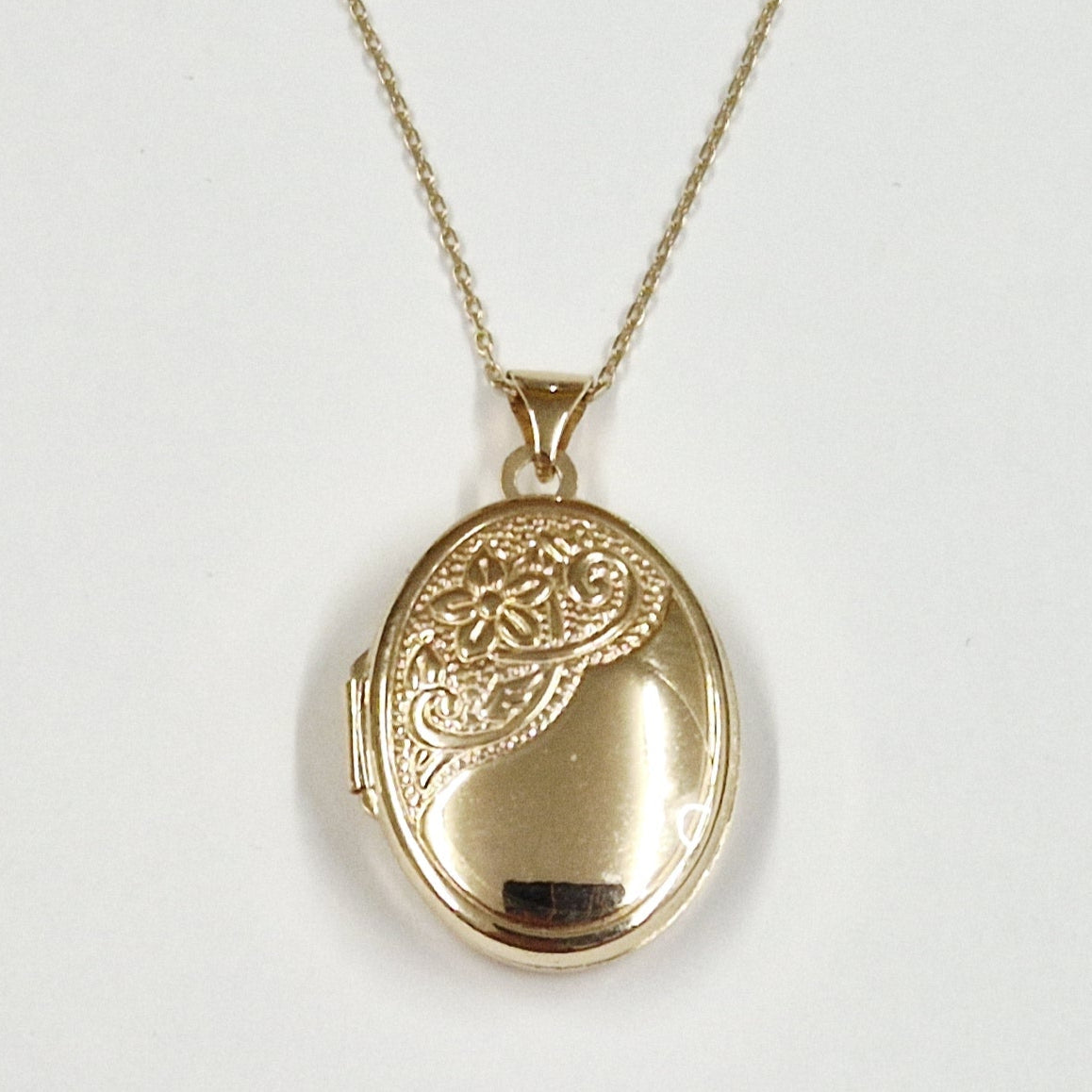 Gold oval locket necklace on a white background