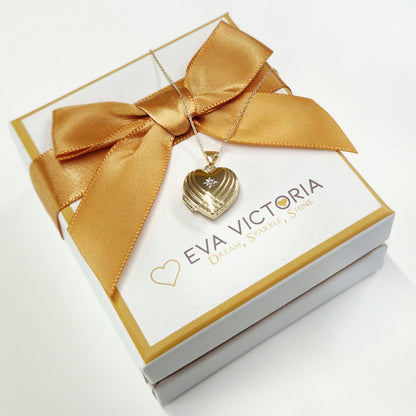 Gold bow and heart-shaped pendant on a card with 'Eva Victoria' branding.